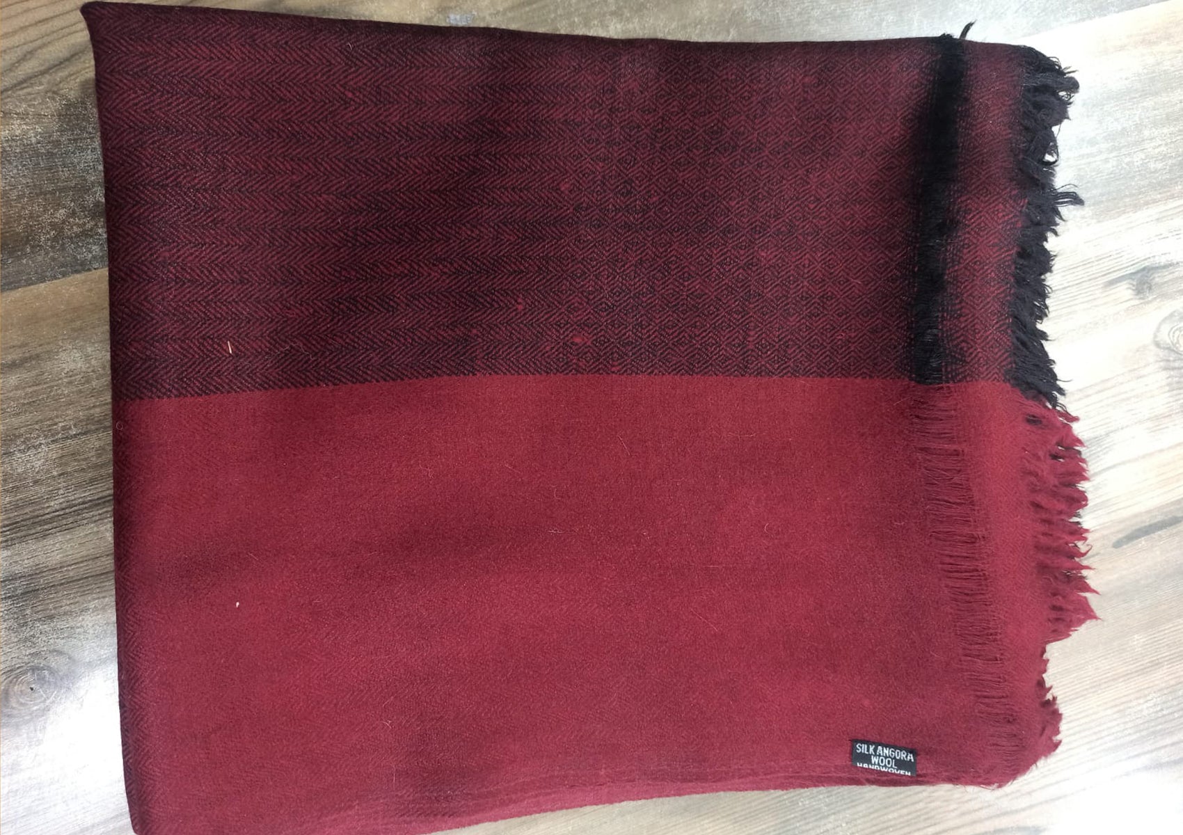 A burgundy meditation shawl folded to display the handwoven fabric detail.