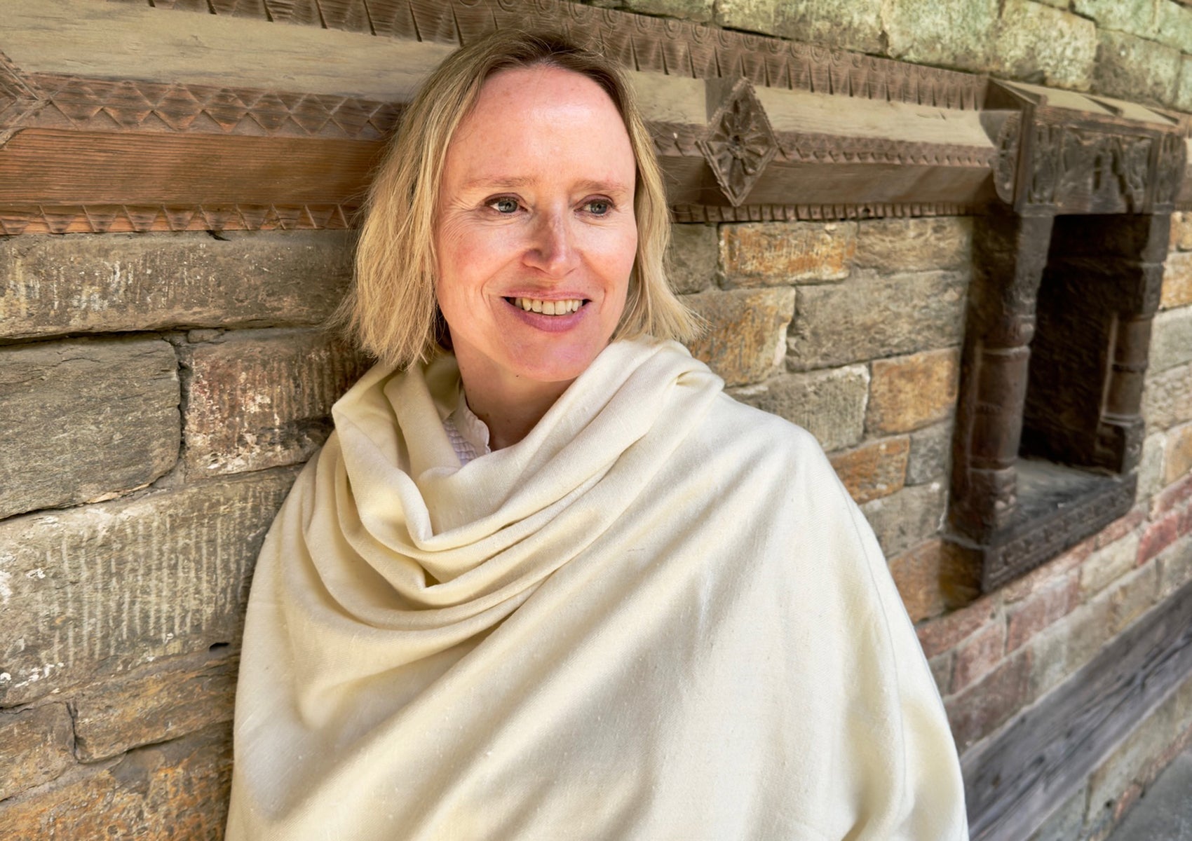 Person meditating in a grand temple, wrapped in a luxurious cream angora shawl with a serene expression.