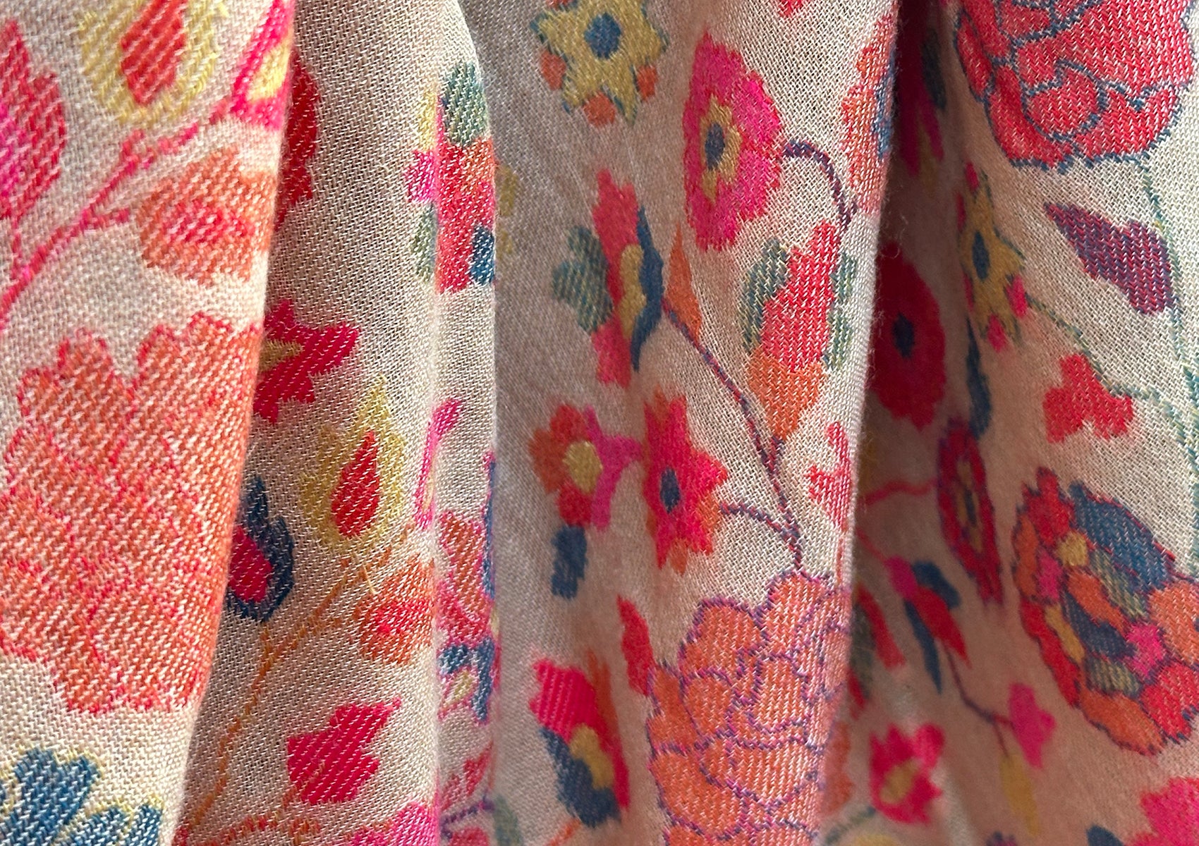 Close-up of intricate floral design on beige Kani shawl.