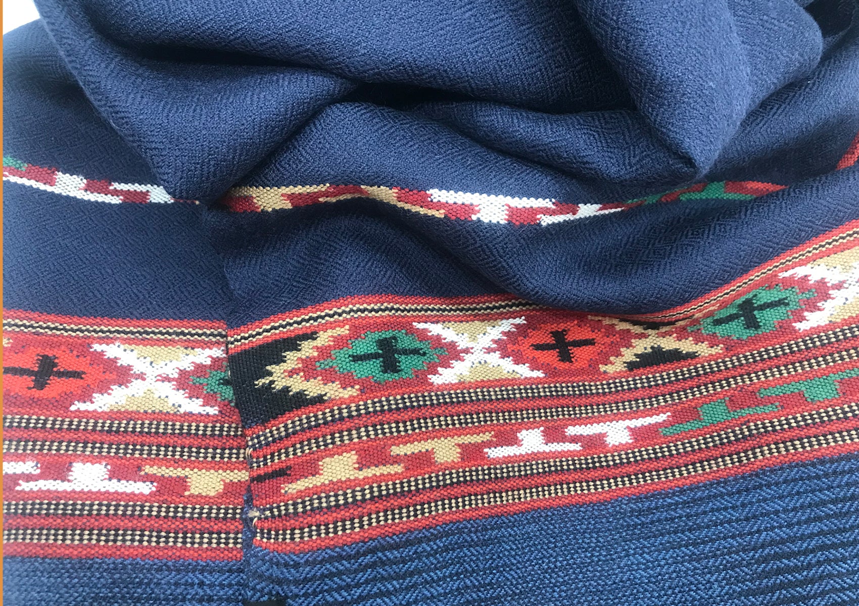 Blue Kullu shawl folded on a surface, displaying traditional ethnic design elements.