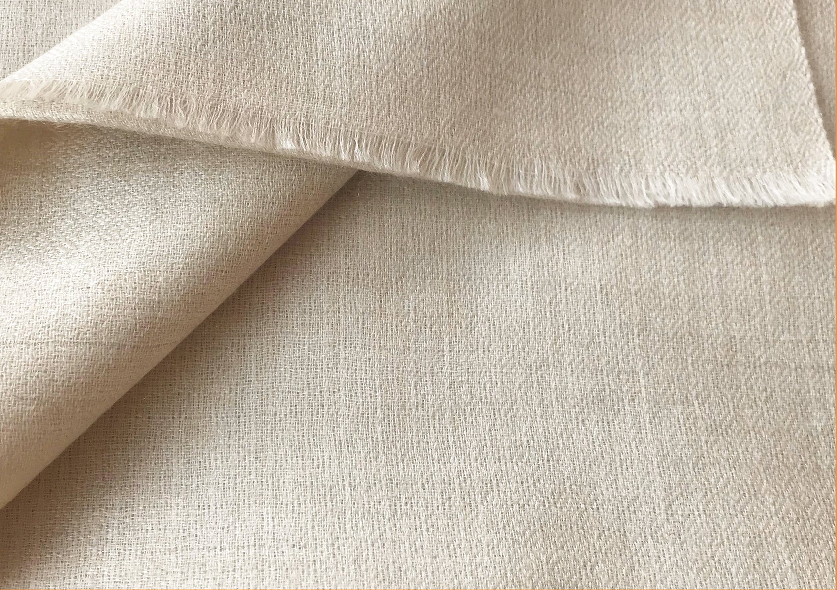 Close-up view of a cream-colored pashmina shawl folded to show fine texture, perfect for winter wear.