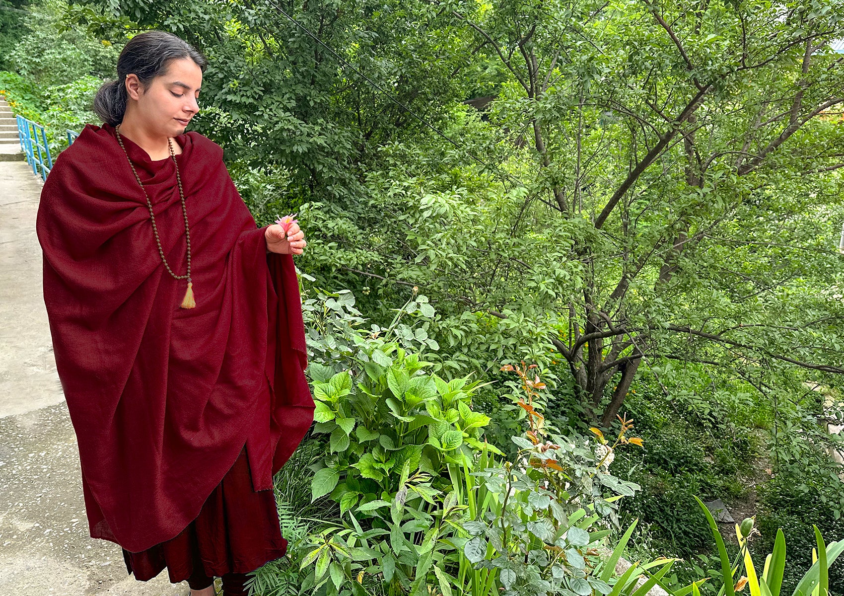 Woman holding a fine merino wool shawl in red.