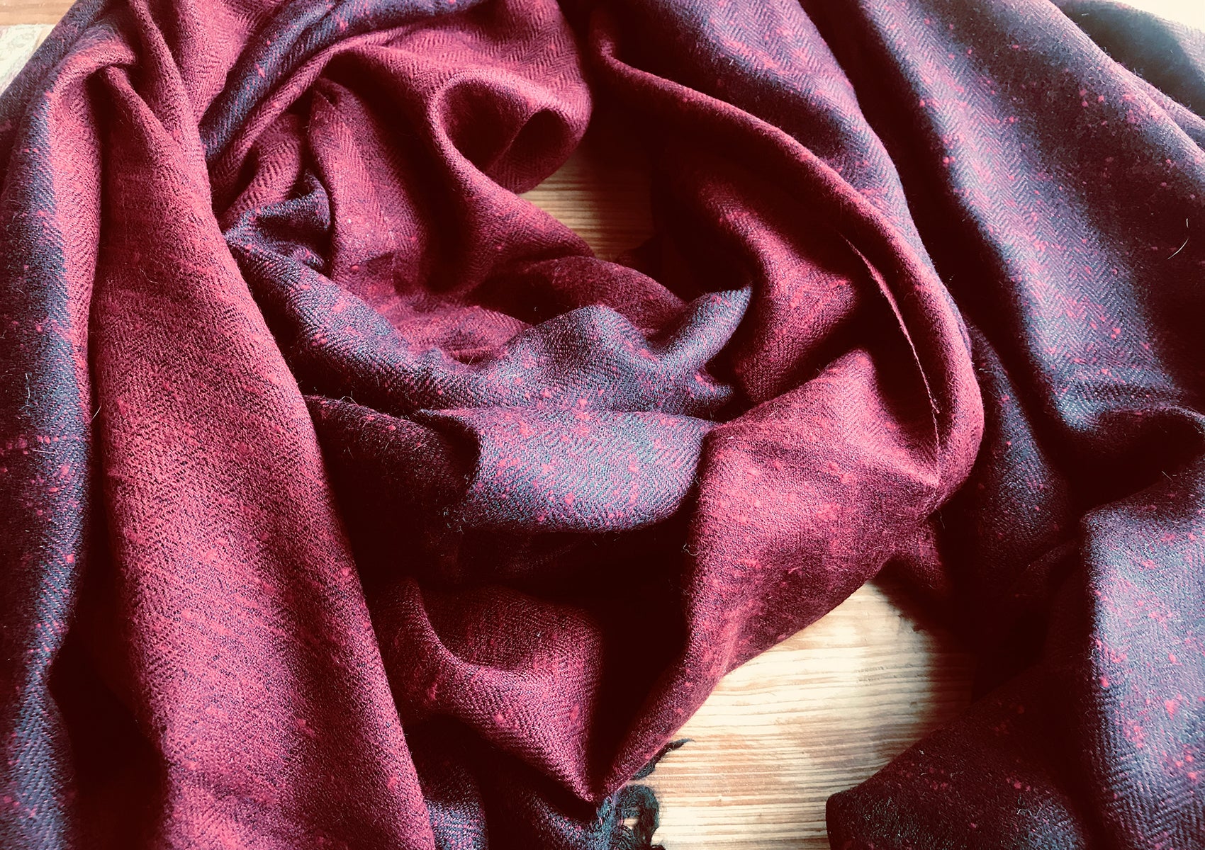 Handwoven red shawl close-up, showing the soft texture and traditional craftsmanship from the Himalayas.