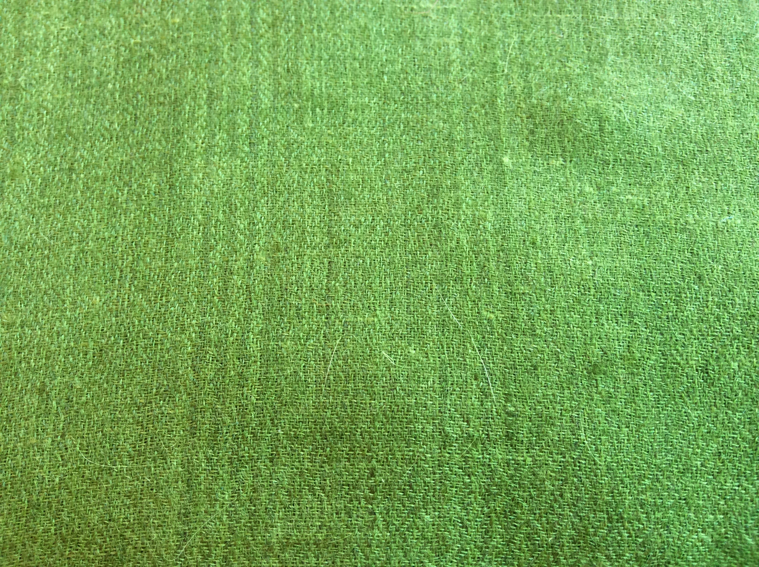 Close-up texture of a lime green wool shawl, showcasing the fine woven fibers and soft material.