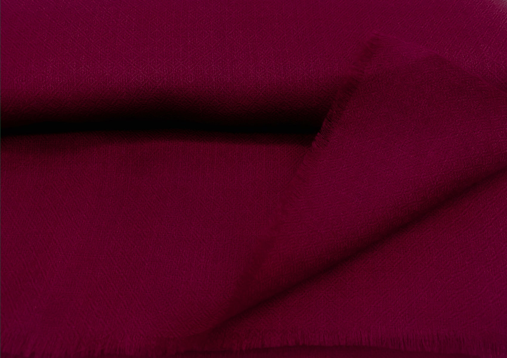 Close-up of a luxurious deep red pashmina shawl showing the intricate fabric texture and fine weave.