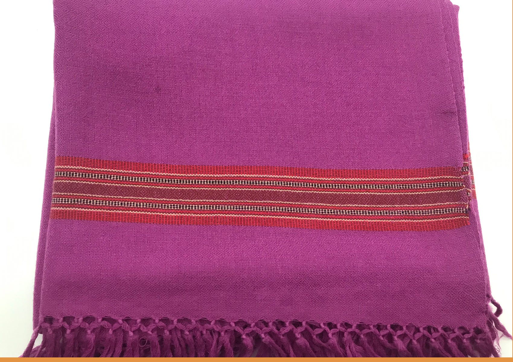 Purple shawl with a red ethnic border and fringed edges, neatly folded to show intricate woven details and craftsmanship.