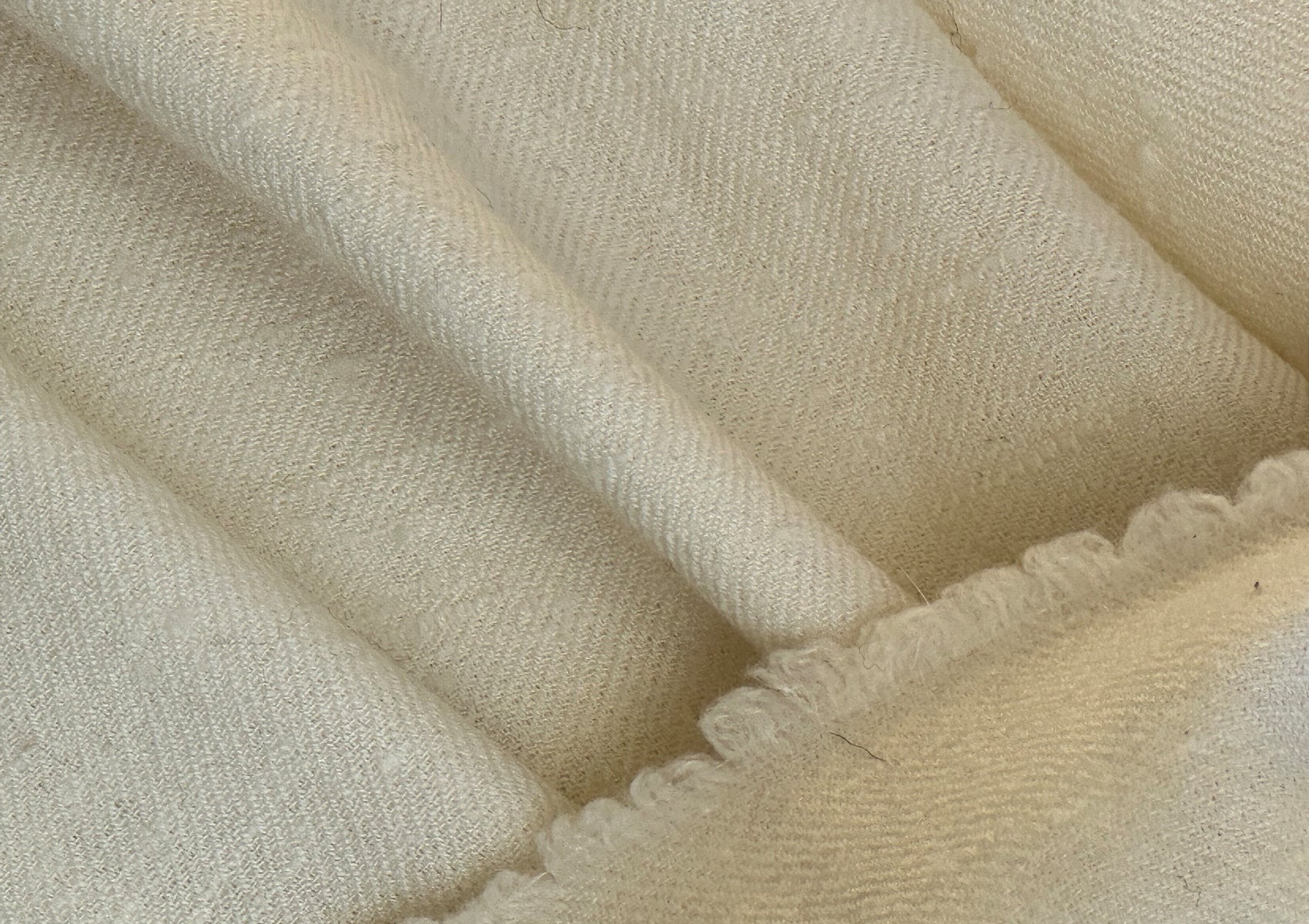 Close detail of the Rasana shawl fabric, showcasing the intricate weave and soft cream hue.