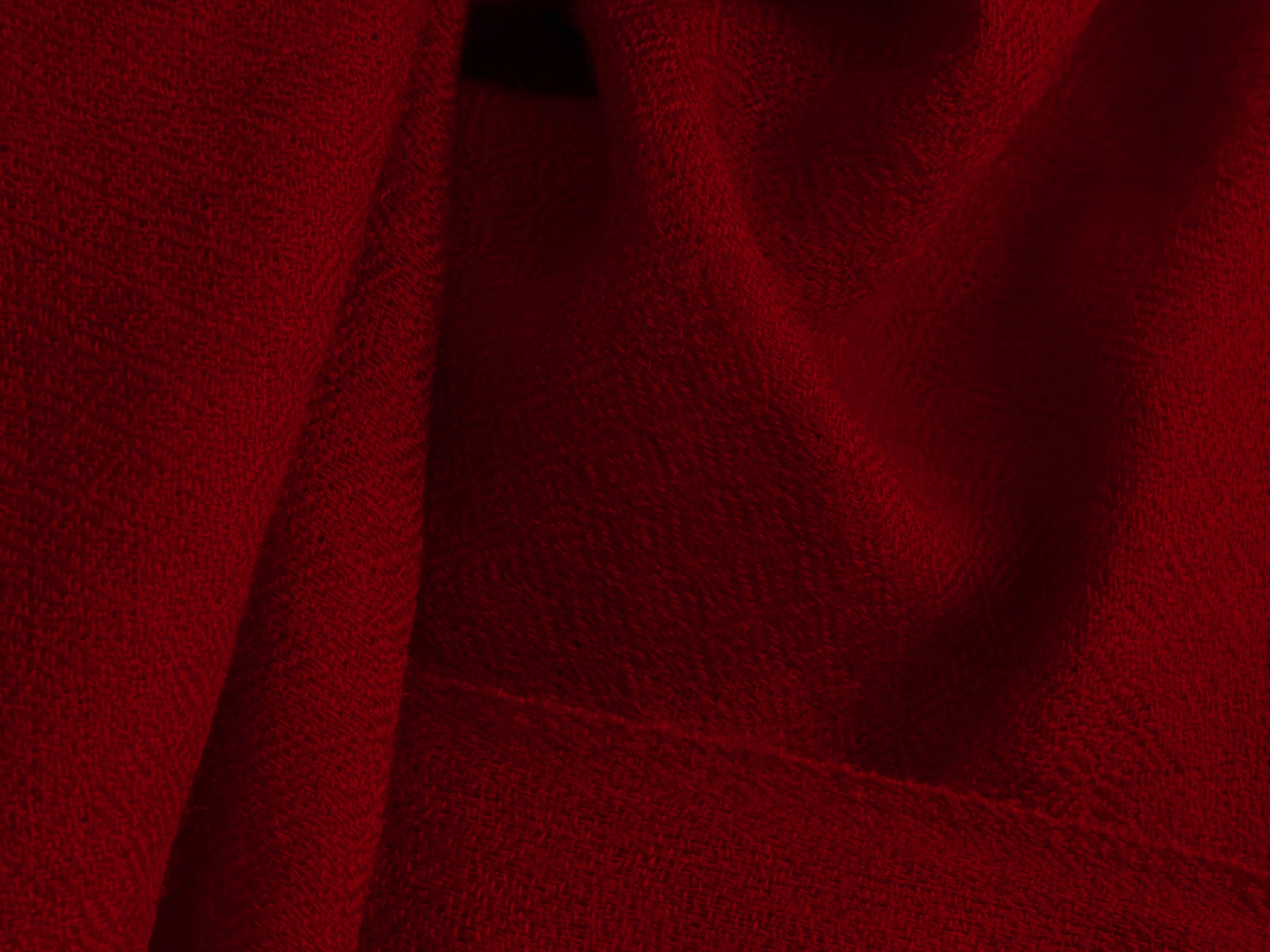 A closer look at the bold and vivid classic red merino wool shawl, showcasing its intricate texture and luxurious fabric. This vibrant piece exudes warmth and elegance, making it an essential accessory for chilly days or special occasions.