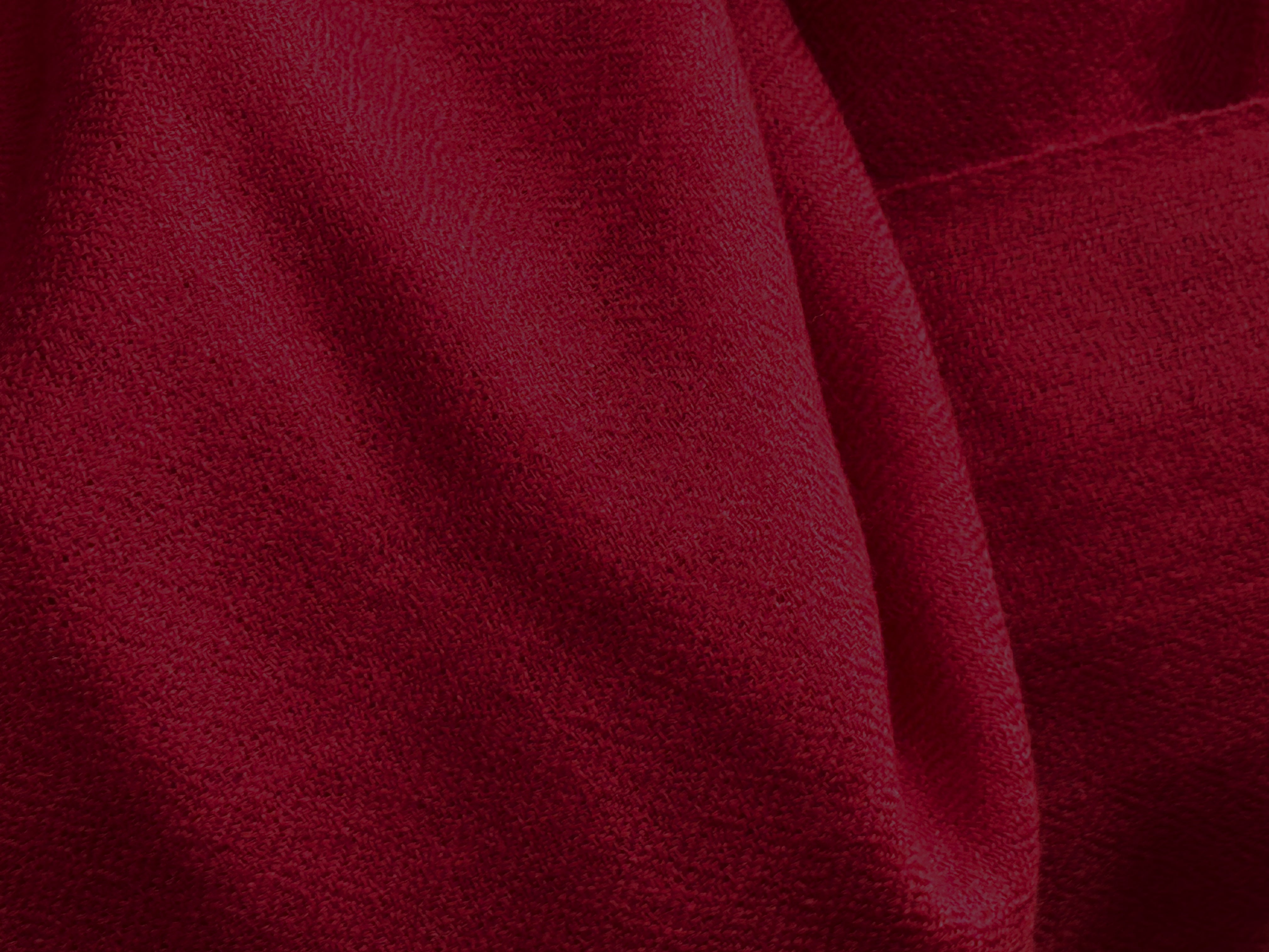 This image highlights the rich texture of a deep red merino wool shawl. Its vibrant hue and fine weave make it a standout piece, ideal for adding a touch of sophistication to any attire. Perfect for keeping warm while embracing a serene aesthetic.