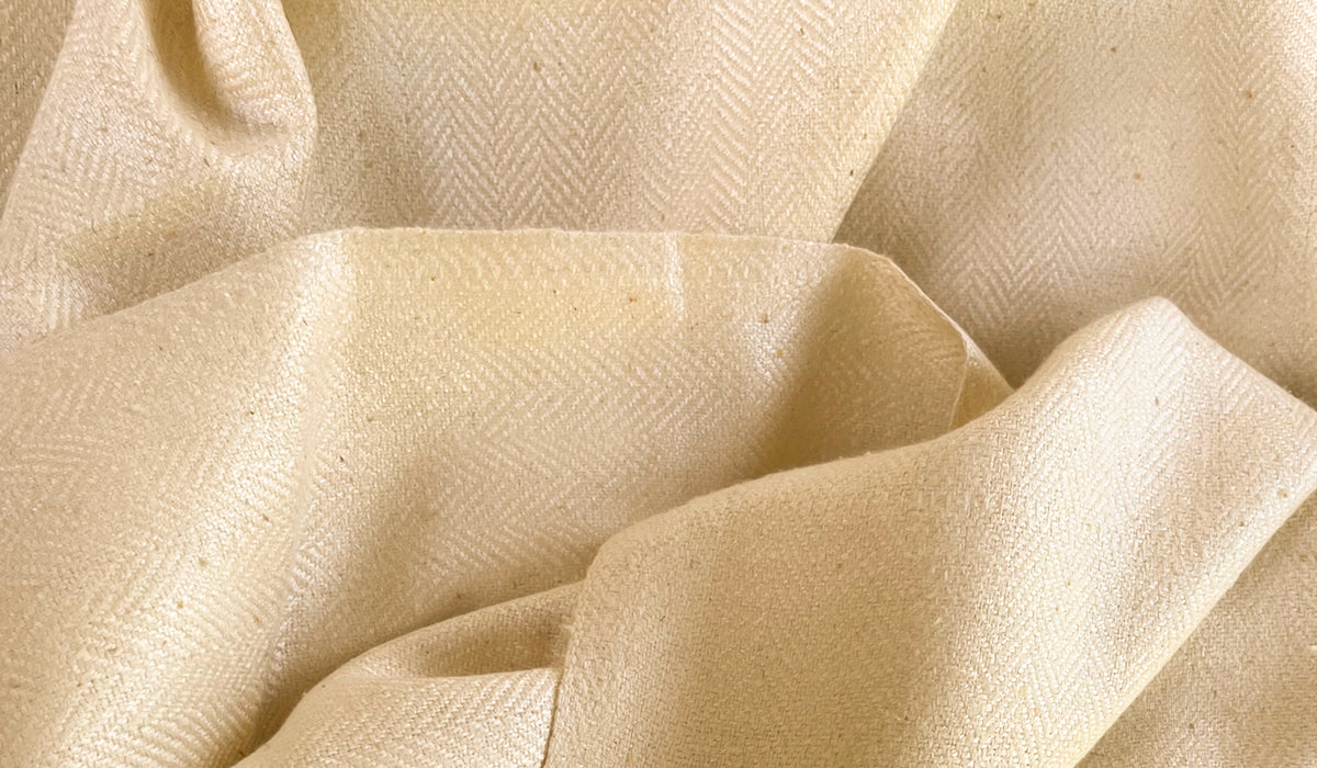 Elegant cream shawl spread out, presenting its luxurious fabric and gentle folds.