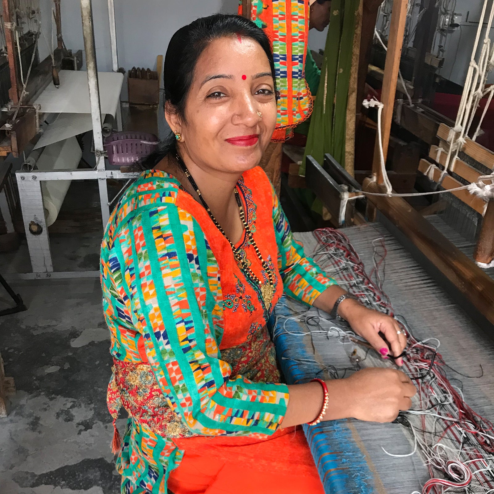 A traditional female weaver in colorful attire, working at a loom, representing cultural craftsmanship and artistry.