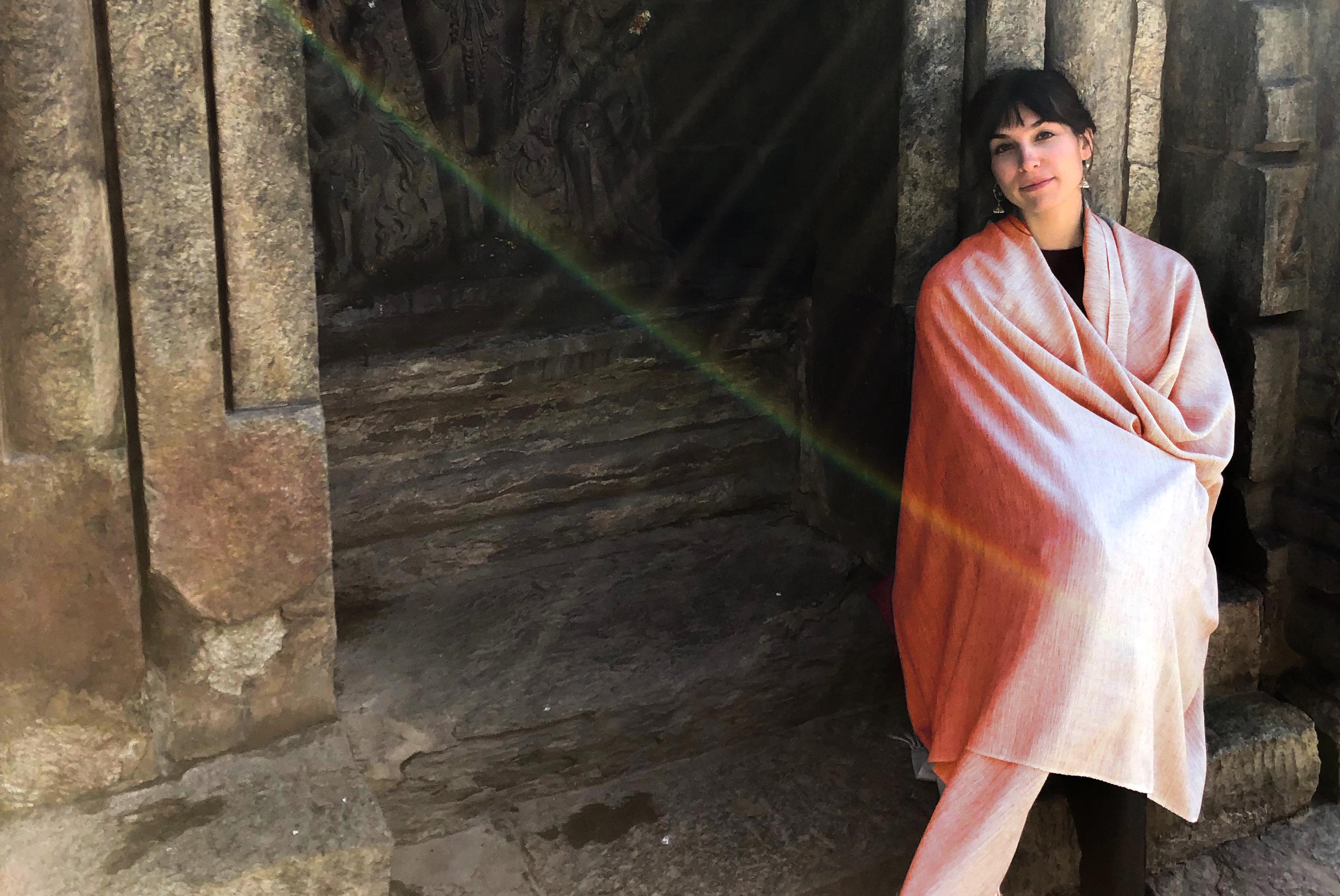 Woman with a pink shawl standing in sunlight, with a beautiful light effect surrounding her.