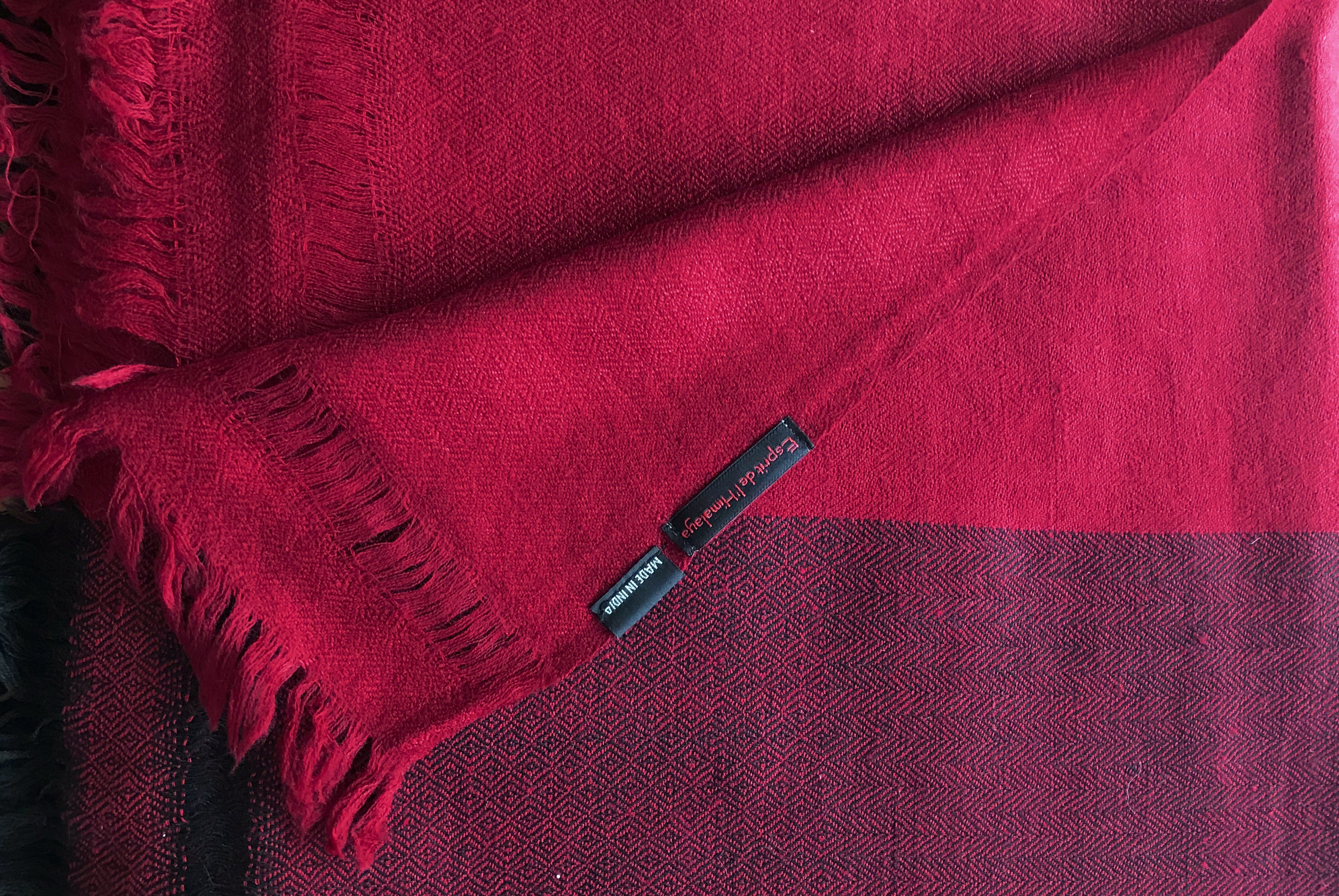 A large handwoven meditation blanket in a deep burgundy shade, folded to show intricate weave patterns.