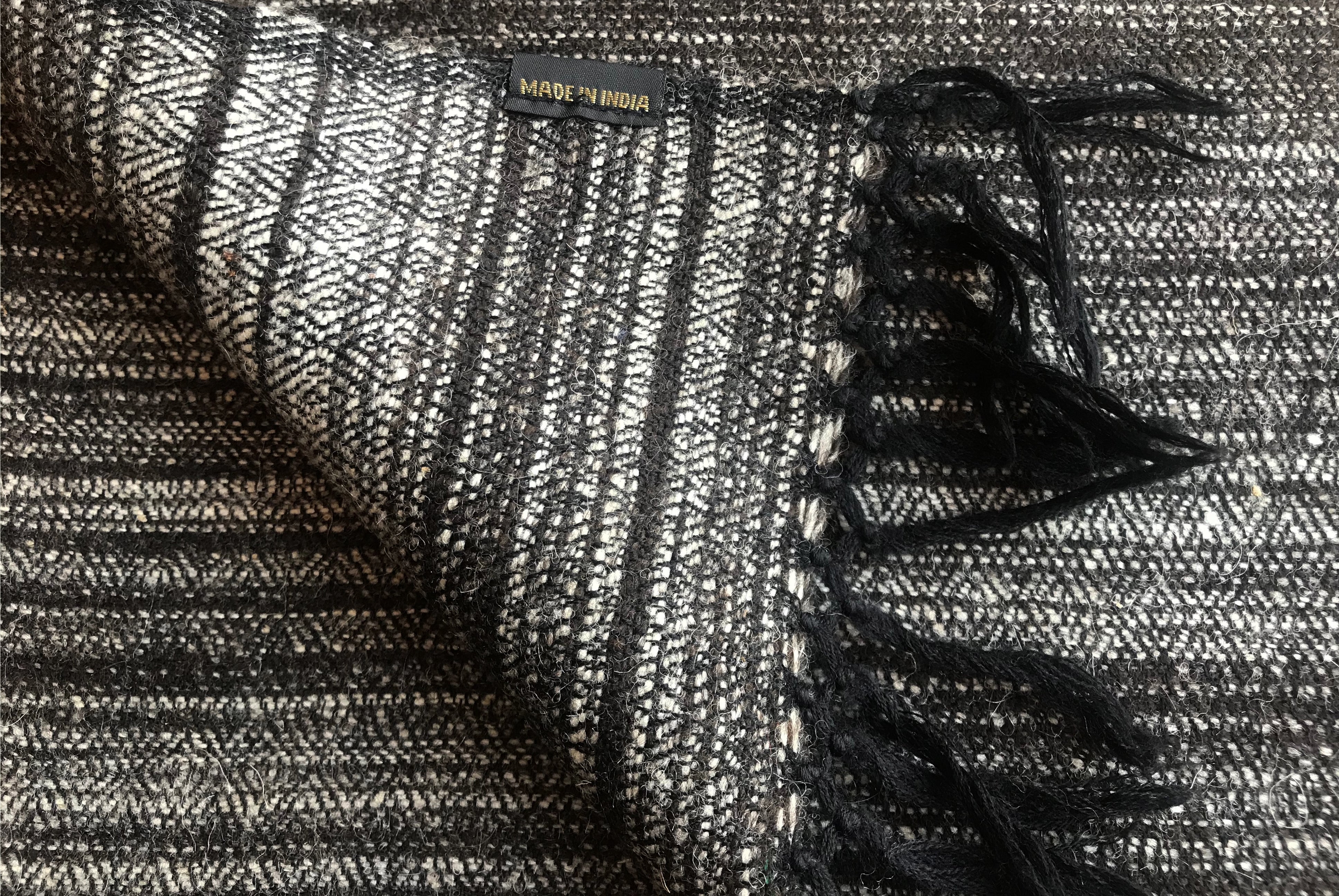 Close-up of a black and white striped yak wool meditation blanket with a fringed border.