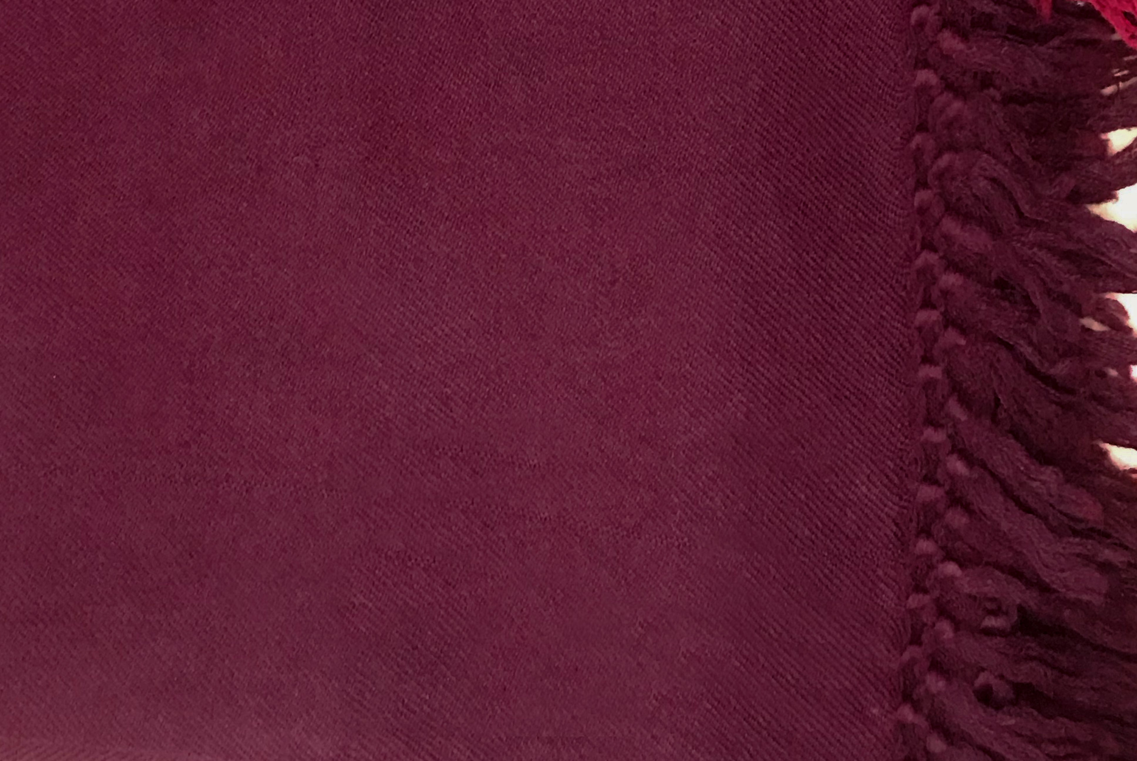 Closeup of burgundy meditation shawl with a serene backdrop, highlighting the shawl's luxurious texture and warm color.