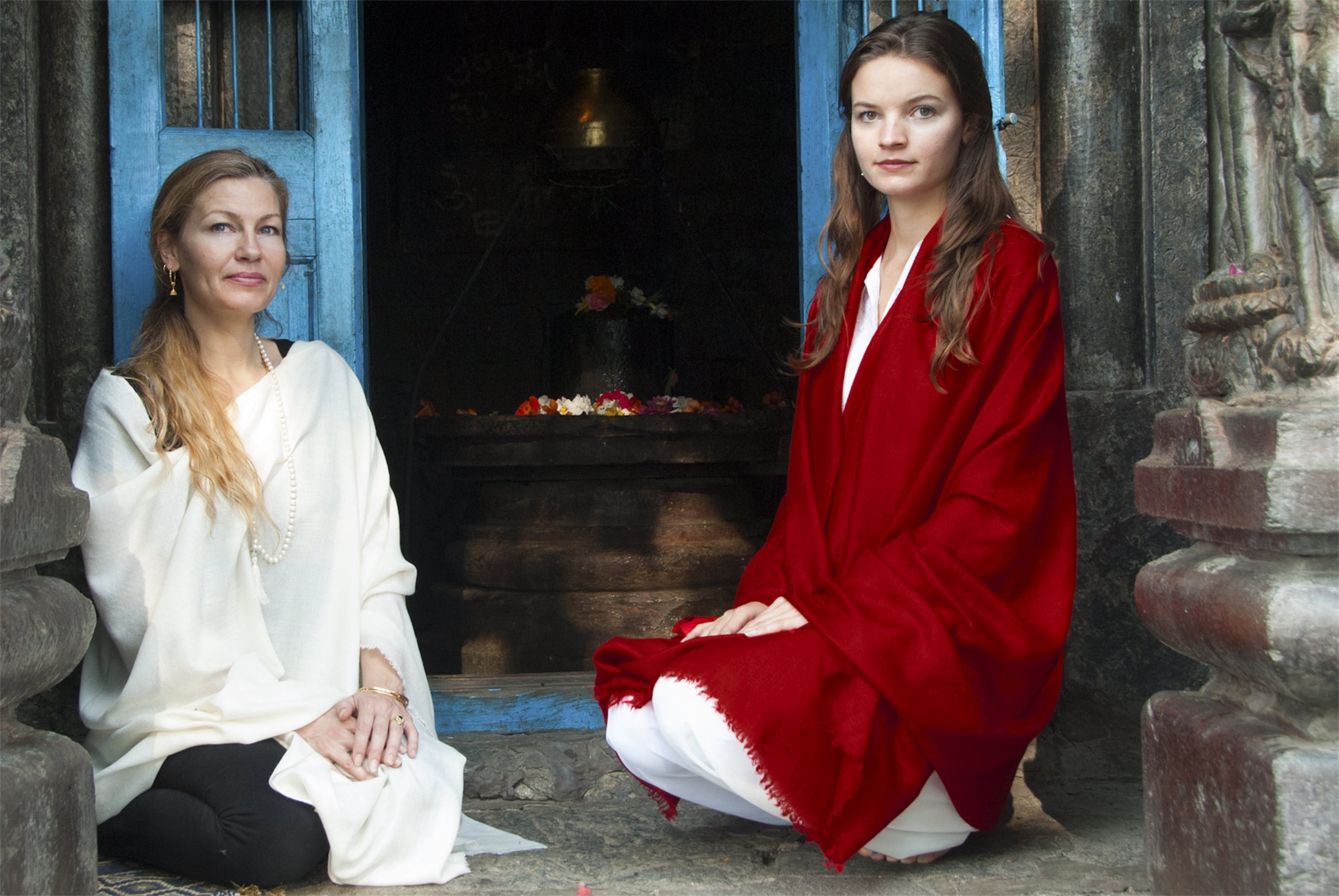 Combination of cream and red bodhisatta meditation shawls draped over two individuals, highlighting the shawls' soft fabric.