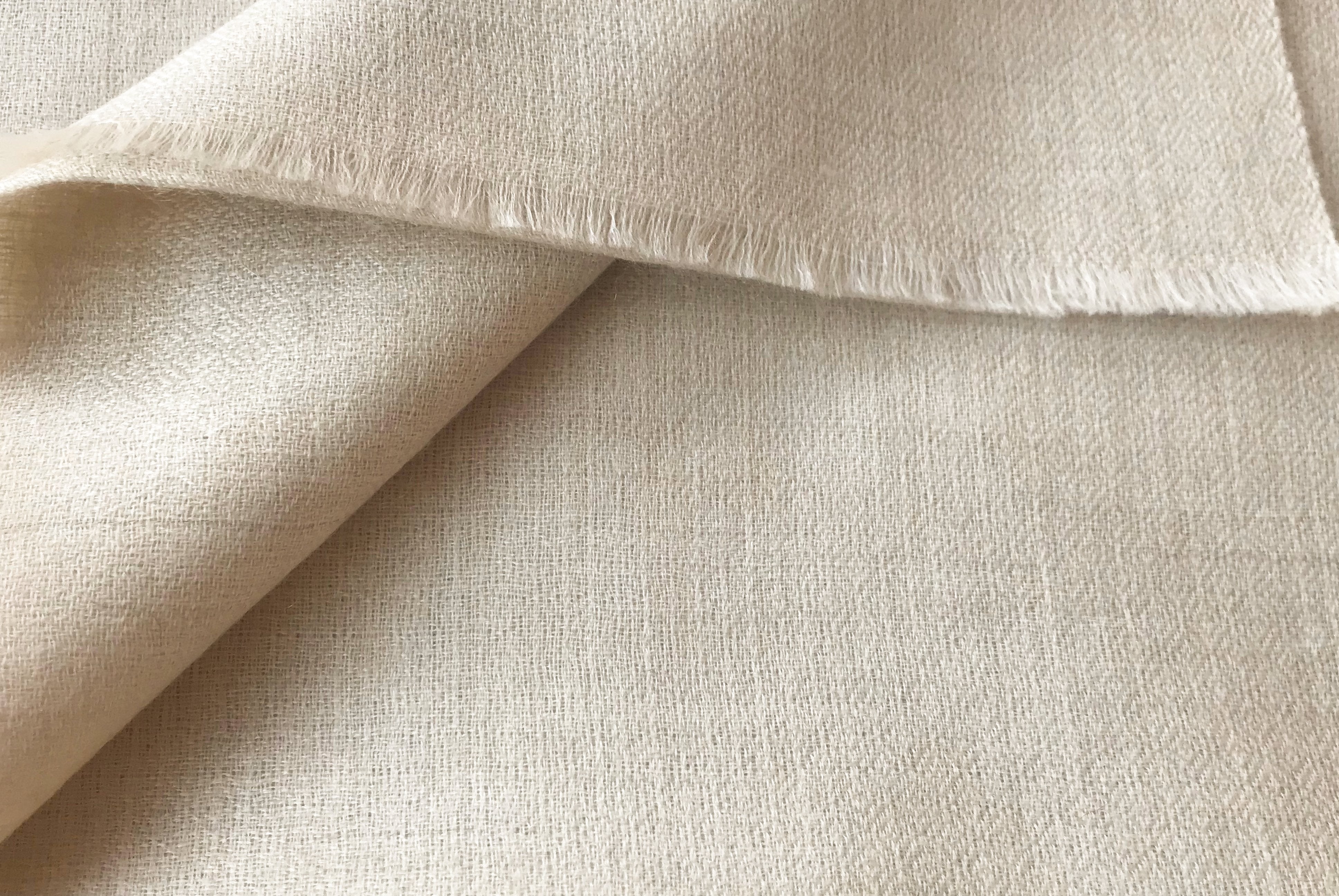 Light cream-colored bodhisatta pashmina shawl, delicately folded to showcase the smooth, soft fabric.