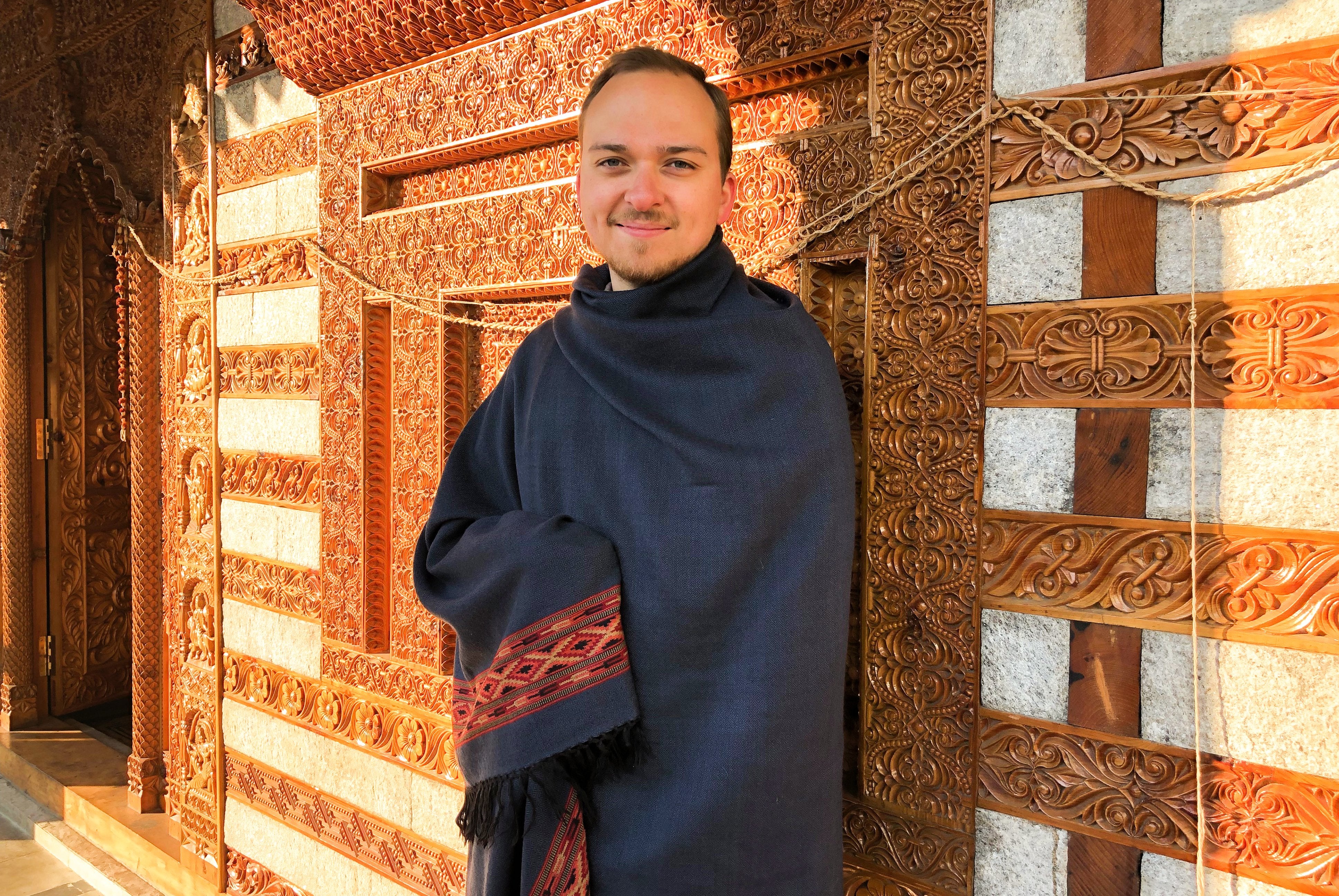 Man with a dark blue meditation shawl featuring ethnic patterns