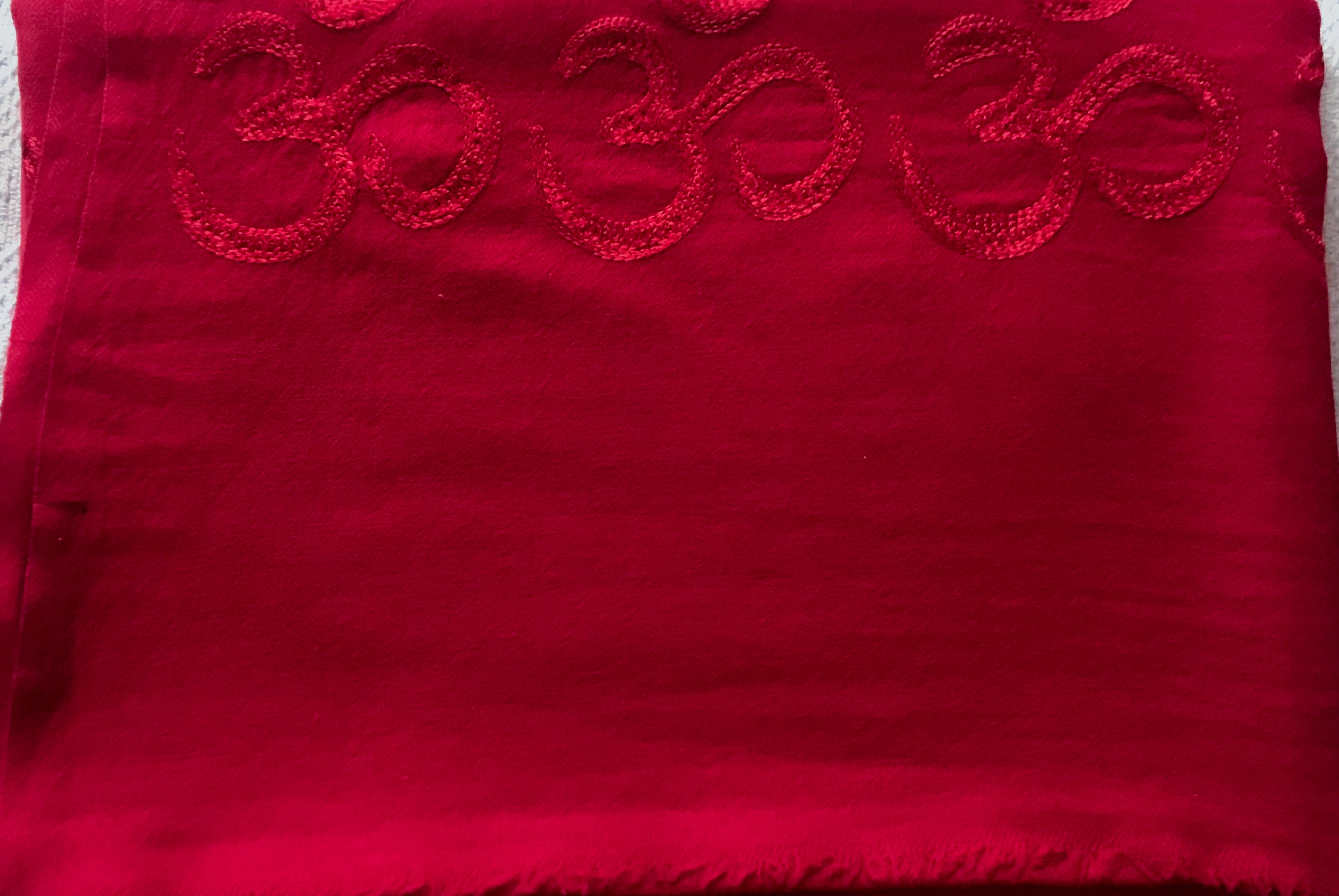 Deep red yoga blanket with the Om symbol, providing warmth and comfort.