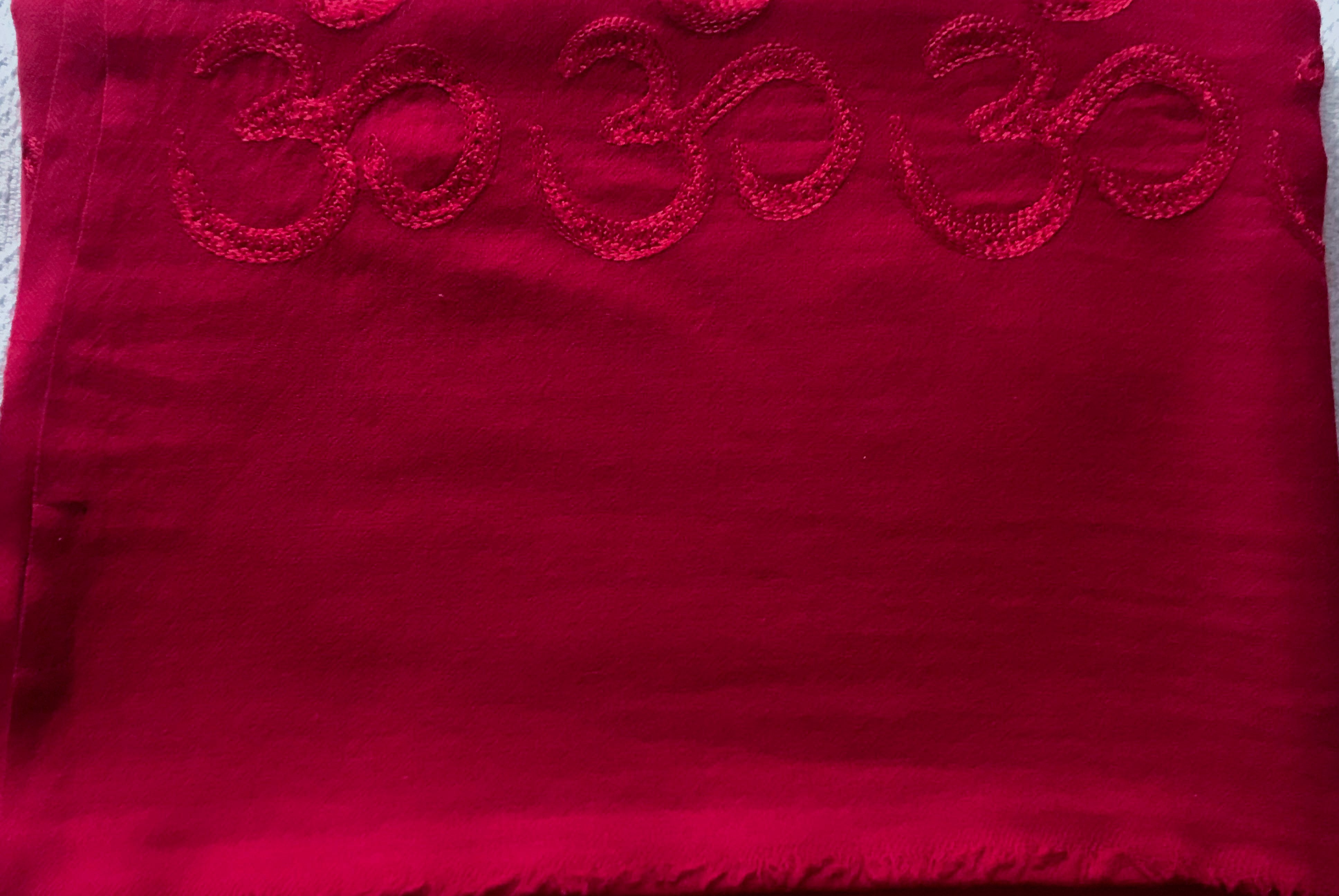 Deep red yoga blanket adorned with Om symbols, providing warmth and comfort.