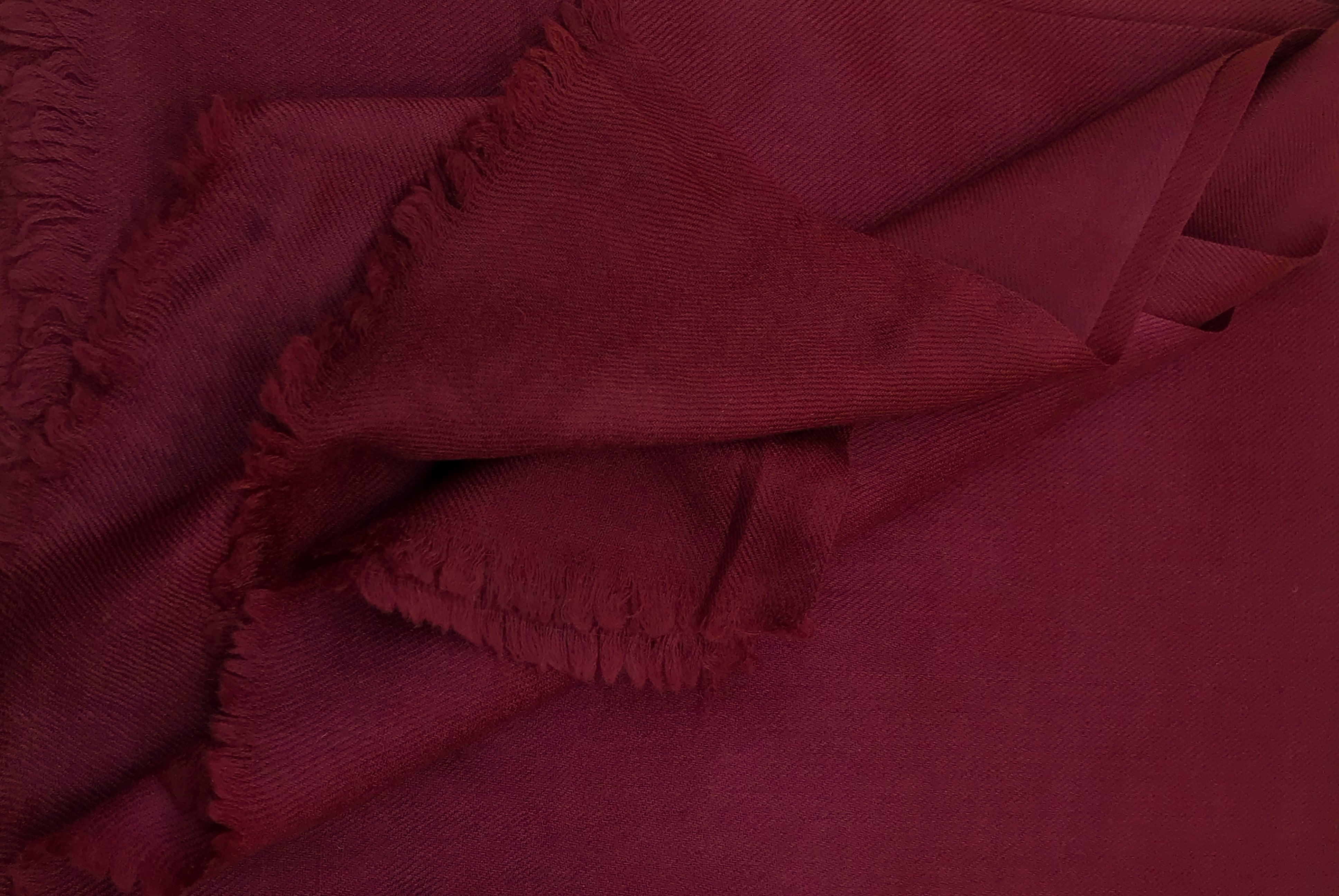 A detailed view of a luxurious burgundy wool shawl from Esprit de l'Himalaya, highlighting its soft, warm texture and delicate fringed edges, perfect for meditation or winter use.