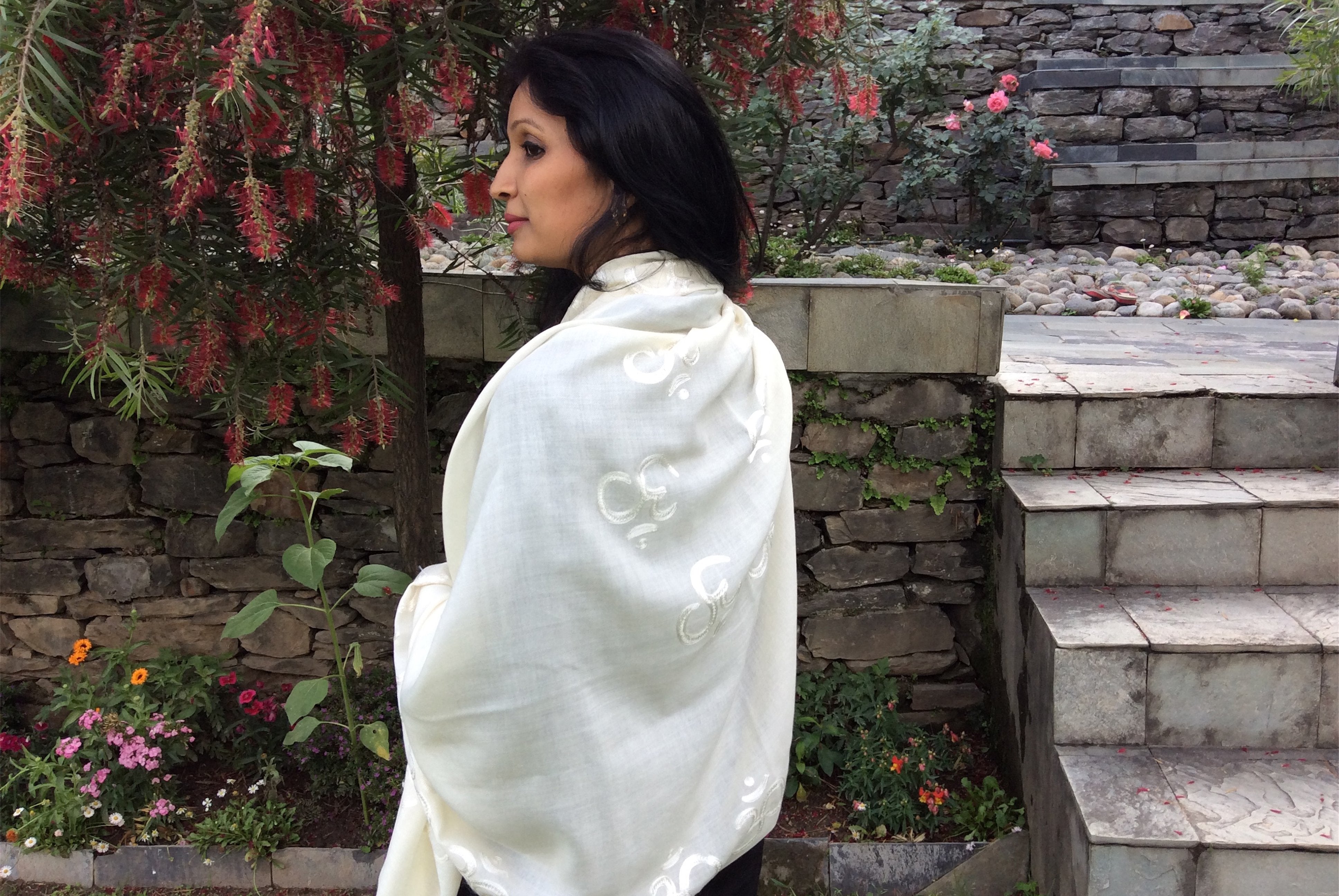 Side view of a woman wearing a white shawl in a garden setting.