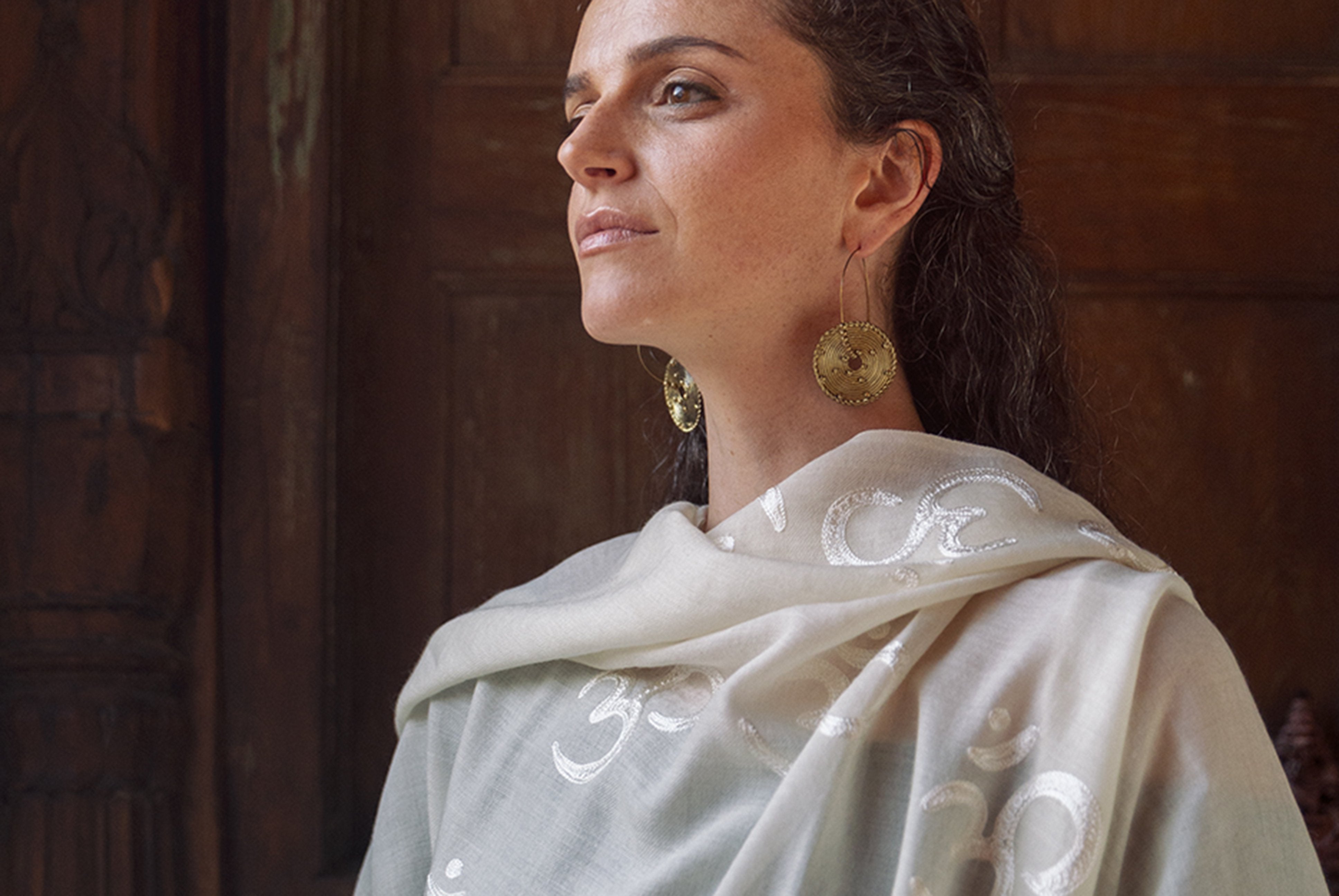 Close-up of woman wearing white shawl with embroidered Om symbols.