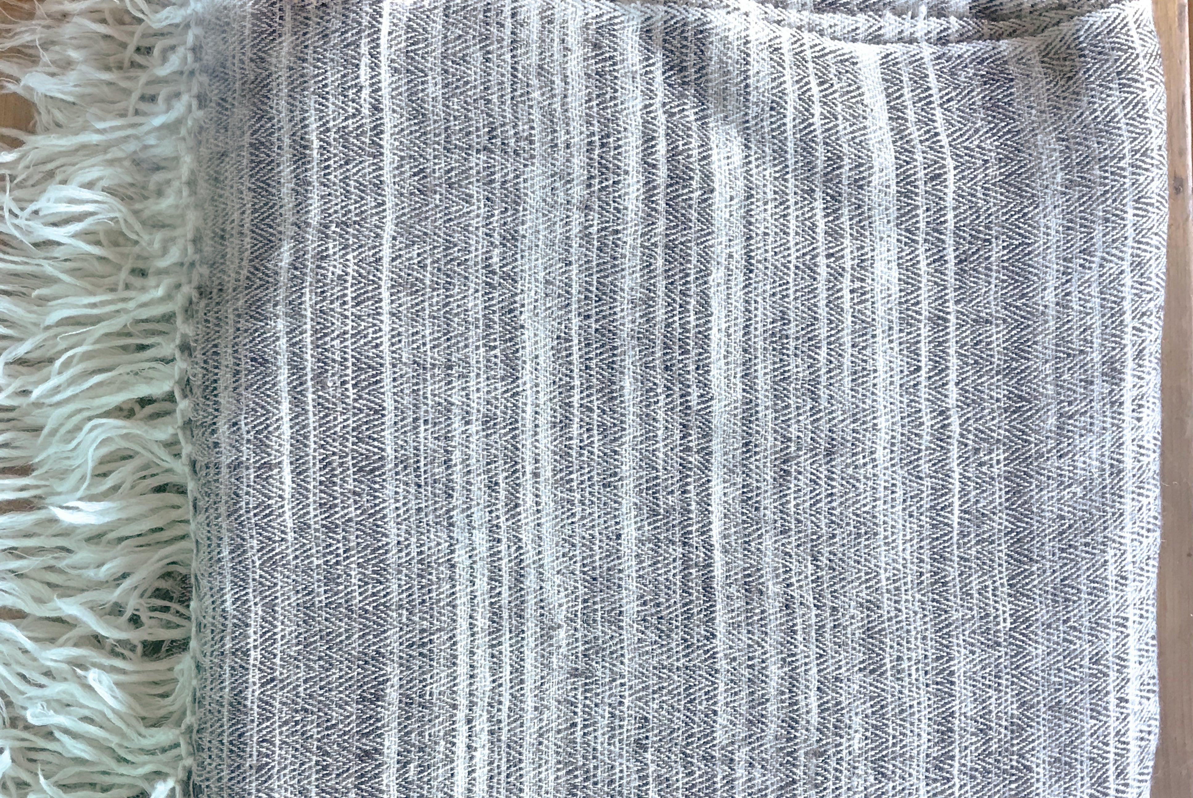 Close-up of a yak wool shawl featuring a classic herringbone pattern with fringed edges, in soft natural tones.